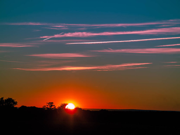 Pôr do sol no pasto com céu romântico com chemtrails e brilho da lente
 - Foto, Imagem