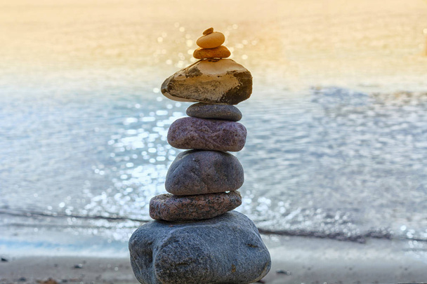 Stones stacked on top of each other on the beach with sea view in the background - Photo, Image