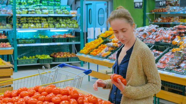 Woman buying fresh red tomatoes at grocery store - Фото, изображение