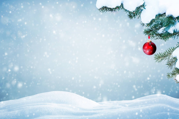 Χριστουγεννιάτικο φόντο με κόκκινο στολίδι και το χιόνι που υπάγονται σε κλαδιά δέντρων πεύκων  - Φωτογραφία, εικόνα