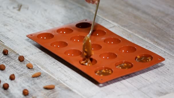 A woman puts in the silicone mold a caramel and nuts filling. - Footage, Video