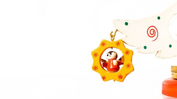 Різдвяний білий квиток прикрашений дерев'яним ангелом, що висить на гілці дерев'яної іграшкової ялинки
 - Фото, зображення