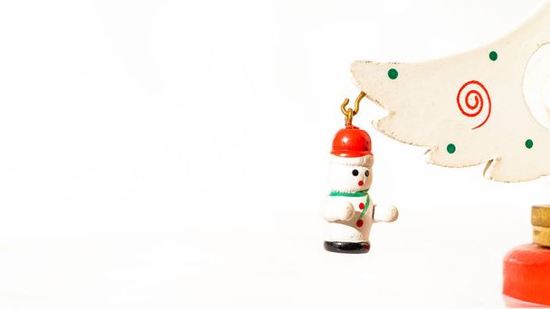 Різдвяний білий квиток прикрашений дерев'яною сніжною маріонеткою, що висить на гілці дерев'яної іграшкової ялинки
 - Фото, зображення