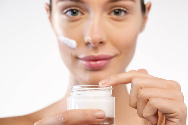 woman holding cream bottle of moisturizing cream for face - Foto, Imagem