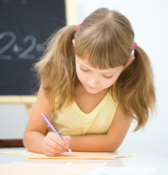 Little girl is writing using a pen - Foto, imagen