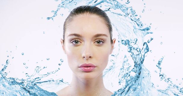 kaunis valkoihoinen nainen, jolla on täydellinen kasvojen iho katselee kameraa, vesi roiskuu taustalla
 - Valokuva, kuva