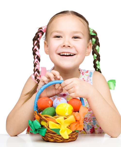 Little girl with basket full of colorful eggs - Foto, imagen