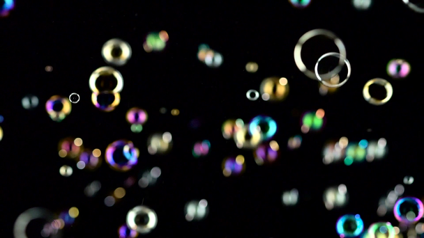 Las burbujas de jabón vuelan y estallan en el aire. En cámara lenta. Fondos negros
 - Metraje, vídeo