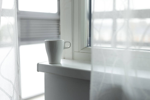 A cup of coffee on the windowsill. Big window. Scandinavian style. Copy space - Valokuva, kuva