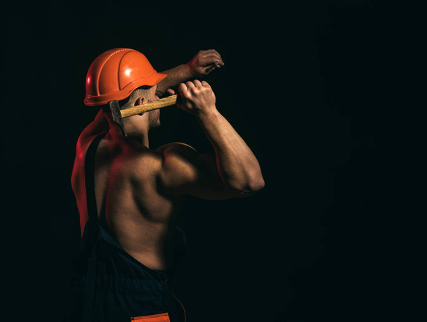 The project is currently under construction. Man work with hammer. Construction worker hammer a nail. Muscular man builder at work under construction. Hard worker use muscular strength, copy space - Valokuva, kuva