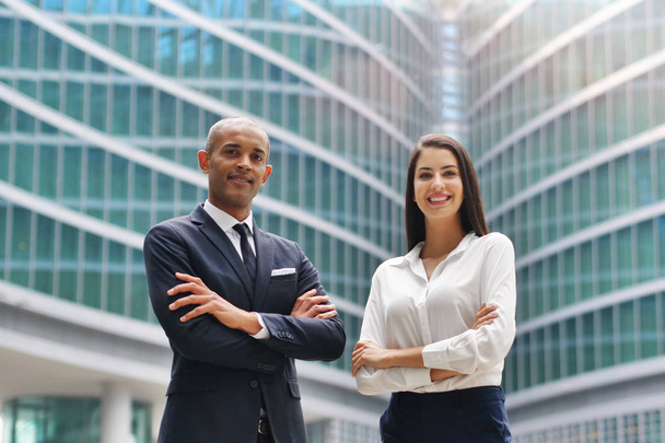 Portrait of a business man and woman of different ethnicity, looking at the camera and smiling, crossing their arms. Concept of: success, finance and team and cooperation. - Photo, image