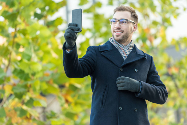 allegro uomo prendendo selfie con albero verde sfocato
  - Foto, immagini