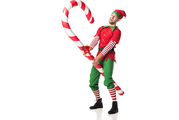 веселий чоловік у різдвяному ельфійському костюмі, що їде на великій цукерковій тростині ізольовано на білому
 - Фото, зображення