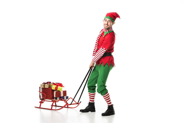 man in christmas elf costume crrying pile of presents isolated on white - Fotografie, Obrázek