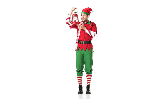 sonriente hombre en traje de elfo de Navidad sosteniendo linterna roja aislada en blanco
 - Foto, imagen