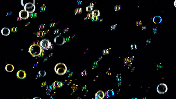 Las burbujas de jabón de colores vuelan. En cámara lenta. Fondo negro
. - Metraje, vídeo