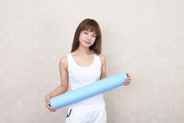 Beautiful woman with a yoga mat at the gym - Fotó, kép