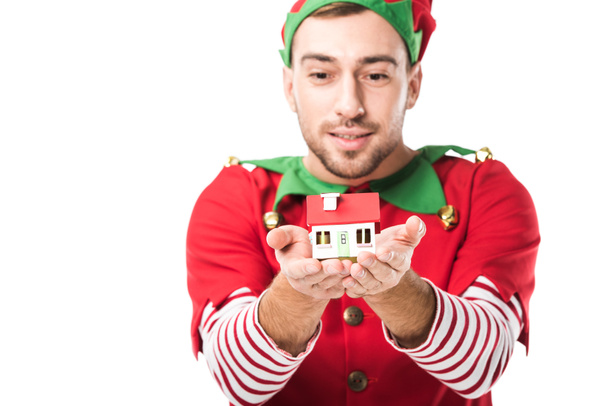 man in christmas elf costume holding house model isolated on white, real estate sale and insurance concept - Foto, imagen