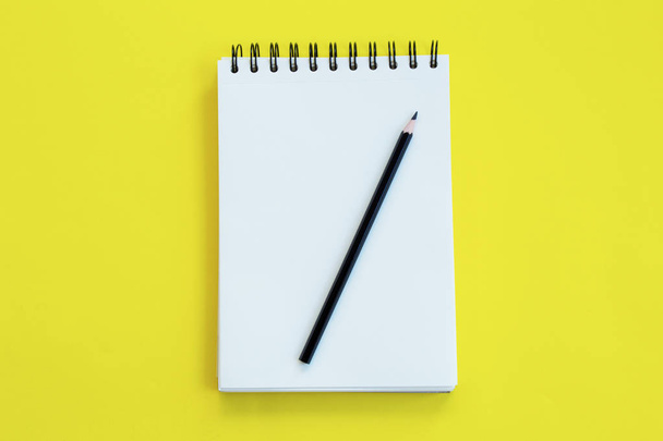 Notebook z ołówkiem na żółtym tle. - Zdjęcie, obraz