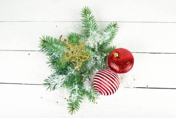 Christmas or New Year ornament. Sprigs of fir and bright decorations on a white wooden surface. - Фото, изображение