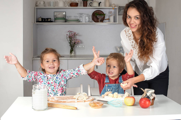 Μικρά παιδιά ψήνουν κέικ με τη μητέρα τους στην κουζίνα στο σπίτι - Φωτογραφία, εικόνα
