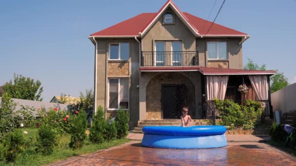 Fiú egy vidéki ház, nyáron a kertben pihenhetnek, játszó víztömlő. - Felvétel, videó