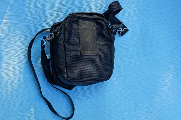 τσάντα μαύρο πανί που βρίσκεται σε ένα φύλλο χαρτί μπλε - Φωτογραφία, εικόνα