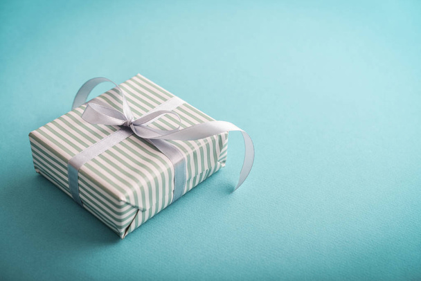 One striped  gift box with grey ribbon on blue background  closeup - Zdjęcie, obraz