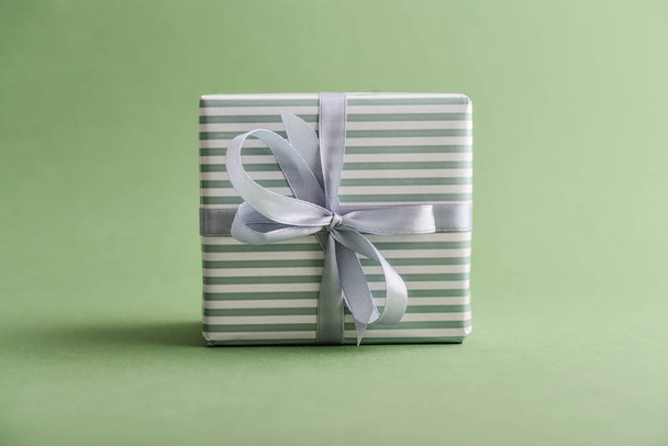 Gift box with gray ribbon on green background closeup - Zdjęcie, obraz
