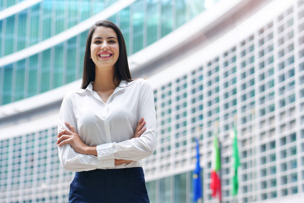 Portrait of a business woman, in a suit and tie, happy and smiling as she looks at the camera and crosses her arms, proud of her work. Concept of: success, finance and female career - Fotoğraf, Görsel