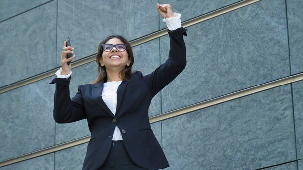 oung beautiful business woman (student) in a suit, smiling, happy, going down stairs, steps, talking on the phone, writing a message. Concept: new business, communication, Arab, banker, glasses, call - 写真・画像