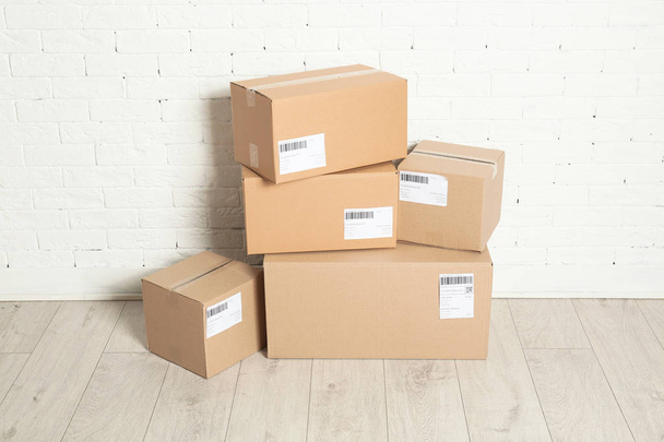 Stack of parcel boxes on floor against brick wall - Fotó, kép