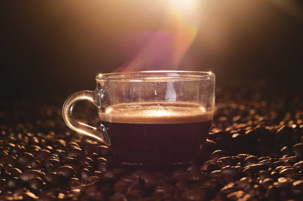 Retrato de uma xícara de café italiano no fundo de madeira com grãos de café para ser moído. Excelente qualidade de café ainda quente e fumegante
 - Foto, Imagem