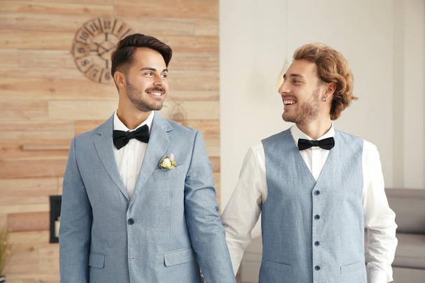 Happy newlywed gay couple in suits at home - Fotoğraf, Görsel