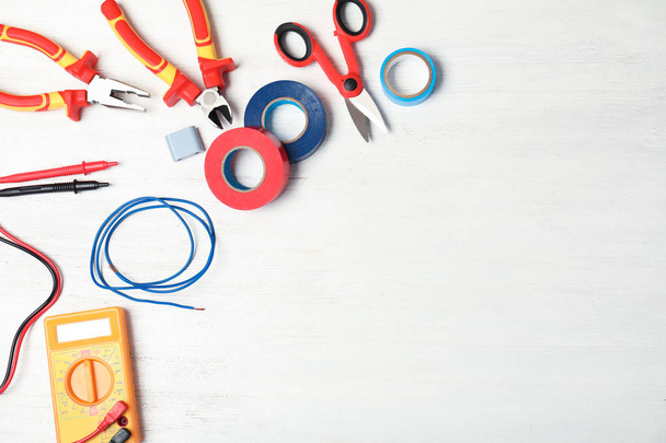 Flat lay composition with electrician's tools and space for text on wooden background - 写真・画像