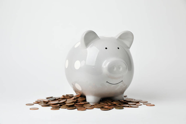 Cute piggy bank and coins on light background - Foto, imagen