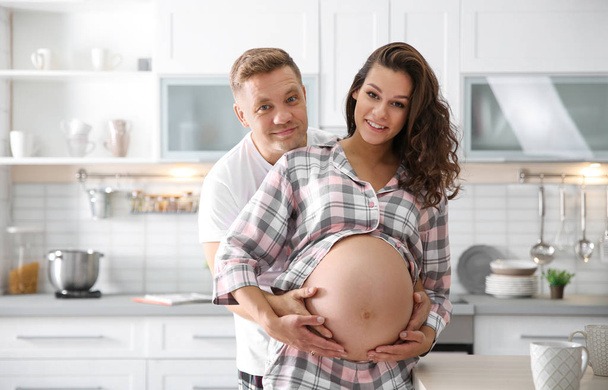 Pregnant woman with her husband in kitchen. Happy young family - Fotoğraf, Görsel