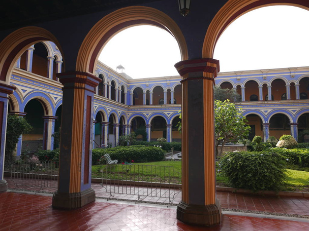 Catholic ancient San Agustin Monastery in Lima. It is located in the historic center of Lima, an UNESCO World Heritage Site. In the photo there is a multi colored colonnade with arches and an ornamental garden - Photo, Image