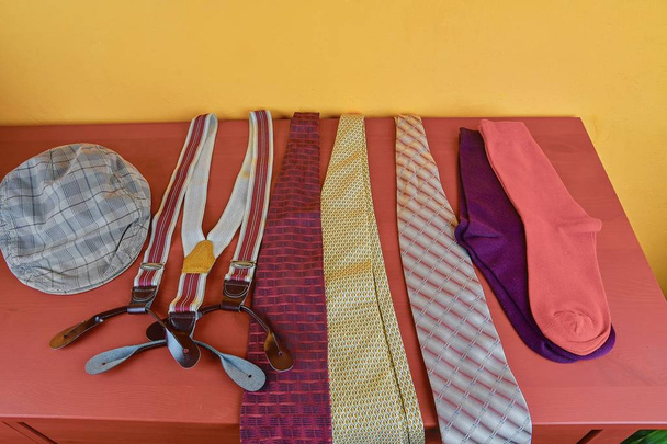 Vestuário de homem. Conceito de vestuário para homens. Meias coloridas, gravatas, aparelho e tampa plana verificada no fundo clarete. Conceito clássico de vestuário masculino
.  - Foto, Imagem