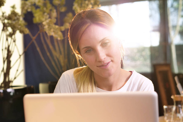 Eine Frau zu Hause nutzt ihren Laptop, um dienstliche E-Mails zu verschicken, online einzukaufen, in sozialen Netzwerken zu surfen. Konzept aus: Einkaufen, Arbeiten, Entspannung und Technik. - Foto, Bild