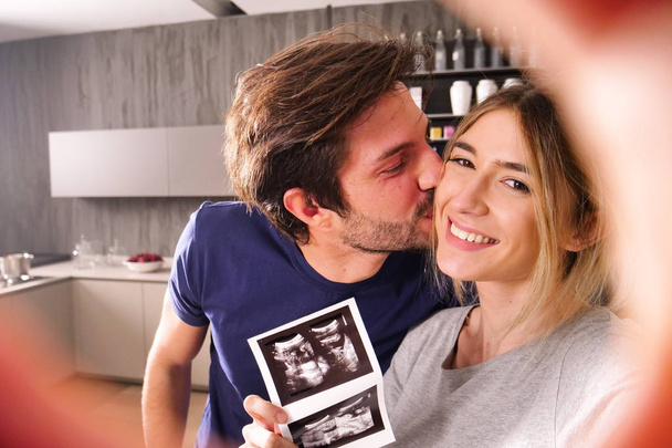 Una pareja casada en el amor videocall sus padres usando una tableta, para anunciar el nacimiento de su hijo mostrando el ultrasonido. Concepto de: familia, nacimiento, vida, amor
 - Foto, imagen