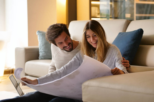 couple in love planning new home furniture while sitting on floor at sofa - Photo, image