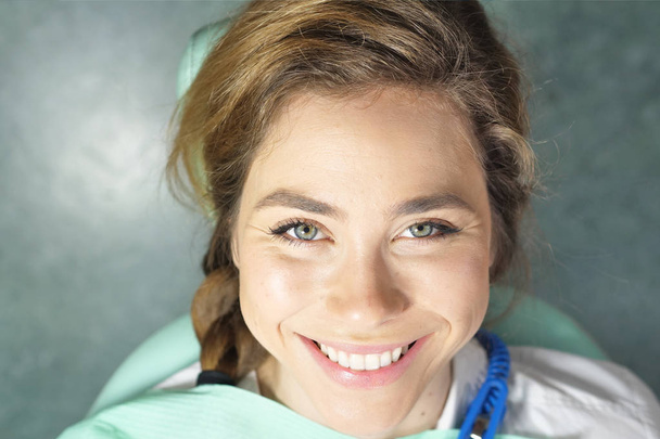V profesionální praxi zubaře zkontroluje chrup pacienta a je spokojená s návštěvou, usměvavý, dokonalé bílé zuby. Koncept: zubaři, zdravotní péče, perfektní úsměv. - Fotografie, Obrázek