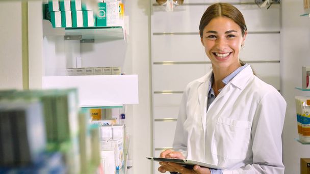 Portrait of a beautiful young girl (woman) pharmacist, consultant, working at a pharmacy, selling and checking medication, smiling, giving advice. Concept: profession, medecine, medical education. - Foto, immagini