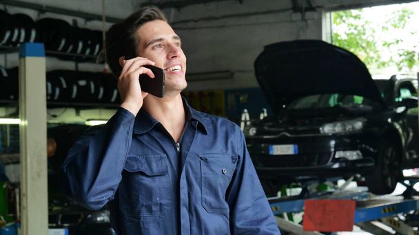In a caretaker a mechanic uses the phone to respond to customer messages and calls as a car customer. Concept of: warranty, security, insurance and assistance, reviews, technology and customer care. - Fotó, kép