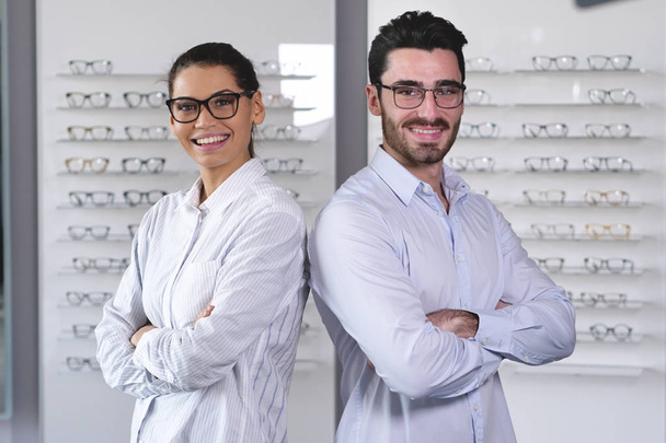 two ophthalmologists woman and man in optical shop with arms crossed - Foto, immagini