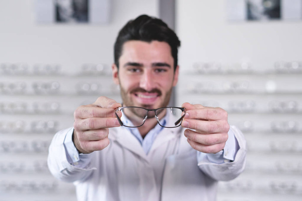 Portrait of ophthalmologist man giving glasses to camera  - Foto, imagen