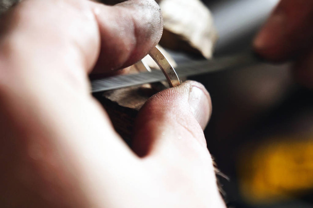 Close up of a goldsmith's hand making a gold or silver ring or a diamond using goldsmith's tools. For this work it takes precision and patience. Concept of: tradition, luxury, jewelry. - Photo, Image