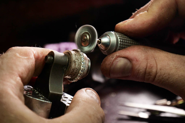 Close up of a goldsmith's hand making a gold or silver ring or a diamond using goldsmith's tools. For this work it takes precision and patience. Concept of: tradition, luxury, jewelry. - Fotó, kép