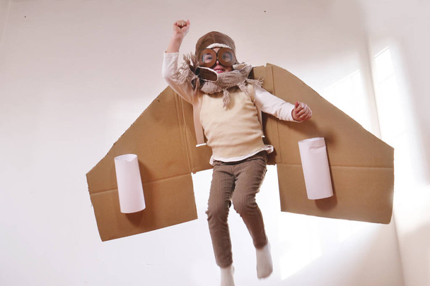 playful little boy dressed as aviator pilot in handmade cardboard box plane  - Photo, image